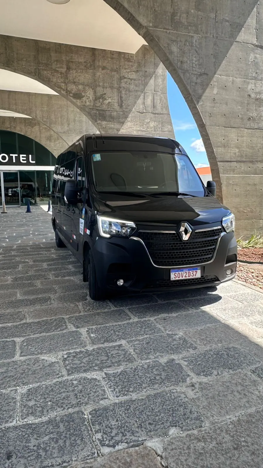 Van black da frota Jompu, uma Renault Master preta, na entrada coberta de um hotel